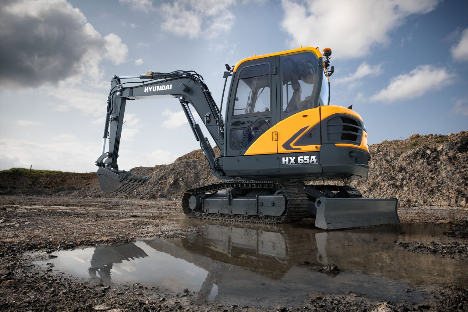 Hyundai Kompakt gravemaskine HX65A der holder parkeret i en vandpyt